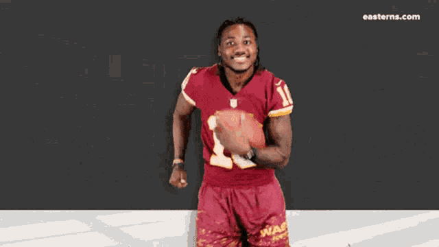 a man in a washington football jersey is holding a football