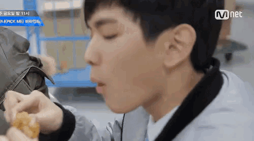 a young man is eating a piece of food with his mouth open .