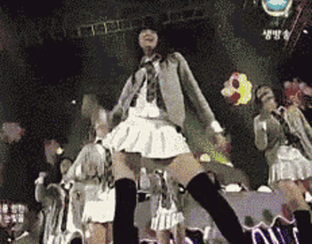 a girl in a white skirt and black knee high socks is dancing on stage