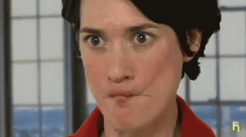 a woman is making a funny face with her mouth open and a window in the background .