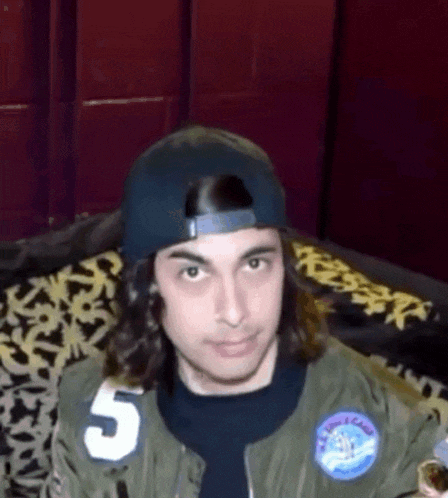 a young man wearing a baseball cap and a jacket with the number 5 on it