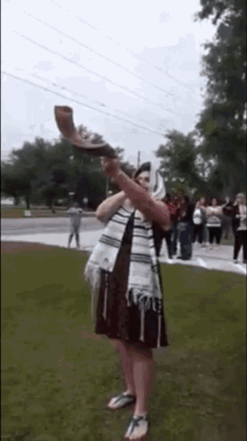 a woman is blowing a shofar horn in a field