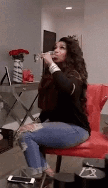 a woman is sitting in a chair drinking from a glass .