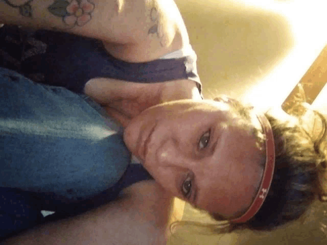 a woman wearing an under armour headband looks down at the camera