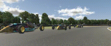 a row of racing cars are driving down a track .