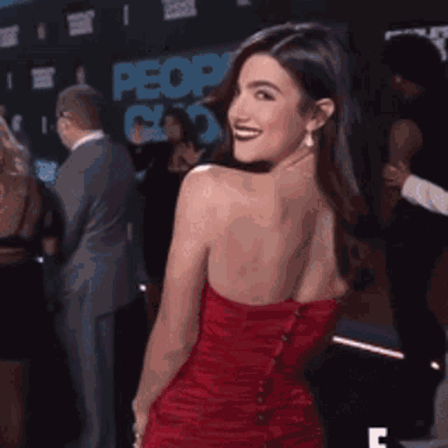 a woman in a red dress stands on a red carpet in front of a sign that says people 's choice
