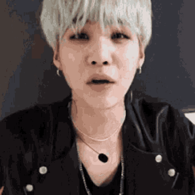 a close up of a person wearing a necklace and a black jacket .