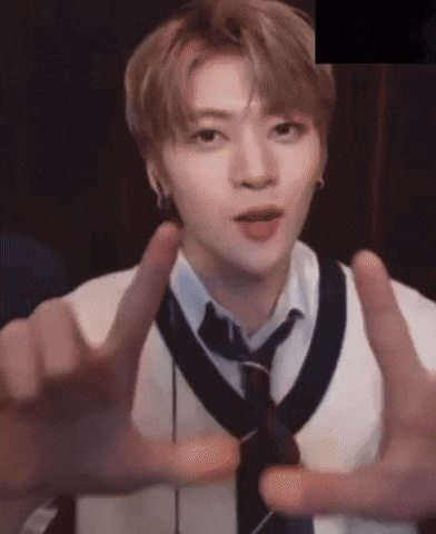 a young man in a white shirt and tie is making a peace sign .