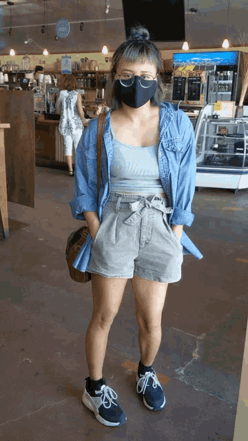 a woman wearing a face mask and shorts is standing in a store