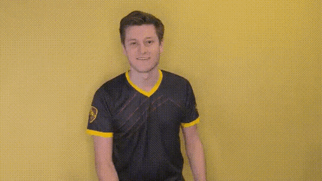 a man in a black and yellow shirt is pointing at something .