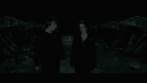 a man and a woman are standing next to each other in a dark room holding hands .