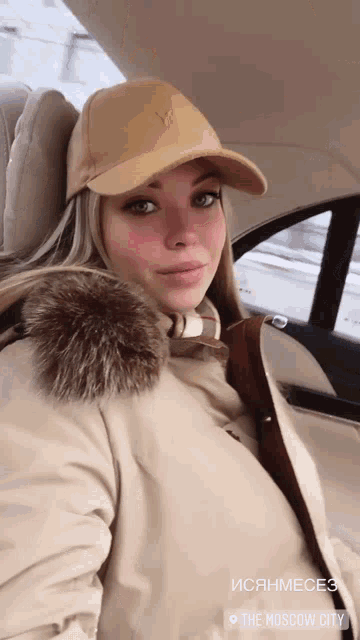 a woman is sitting in a car with the moscow city written on the bottom right