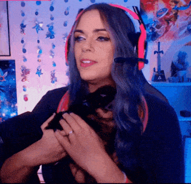 a woman wearing headphones is holding a small black animal