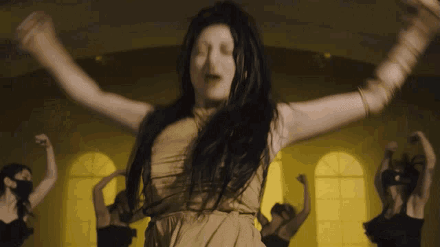 a woman in a yellow dress is surrounded by a group of dancers