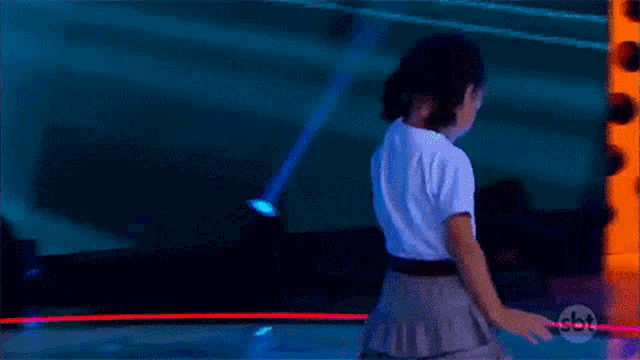 a little girl is standing on a stage in front of a sbt logo