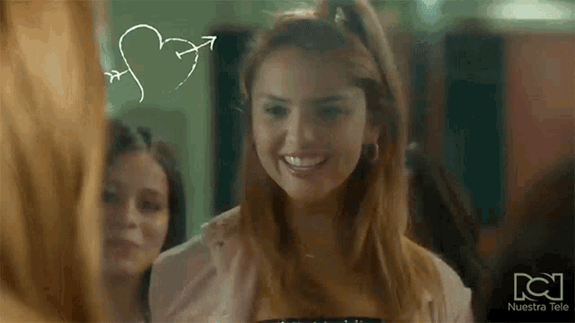 a woman is smiling and looking at herself in a mirror with a heart drawn on it .