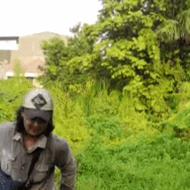 a man wearing a hat and sunglasses is standing in a field of grass .