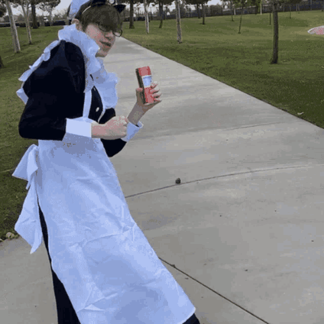 a woman in a maid costume is walking down a sidewalk holding a can of soda