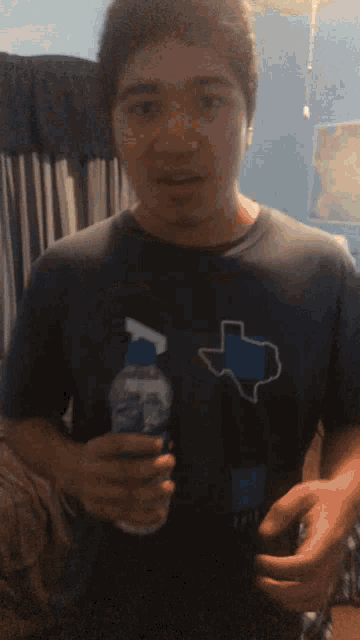 a man in a texas shirt is holding a water bottle