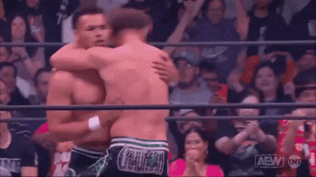 two wrestlers are posing for a picture in a wrestling ring .