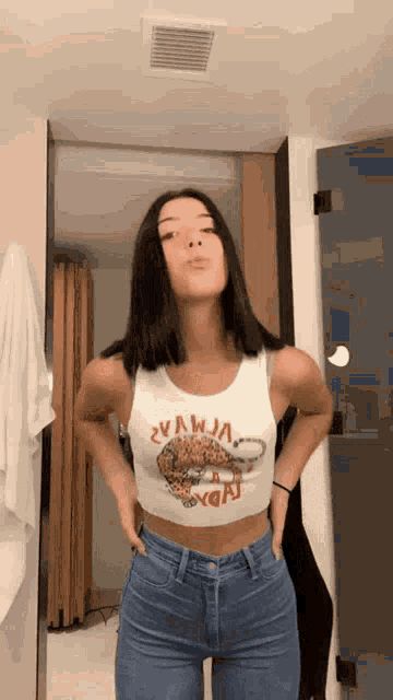 a woman in a crop top and jeans is standing in front of a door .