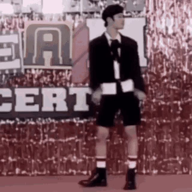 a man in a suit and shorts is standing on a stage .