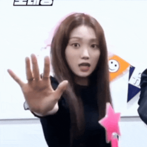 a woman with long hair is making a funny face while holding a pink star in her hand .