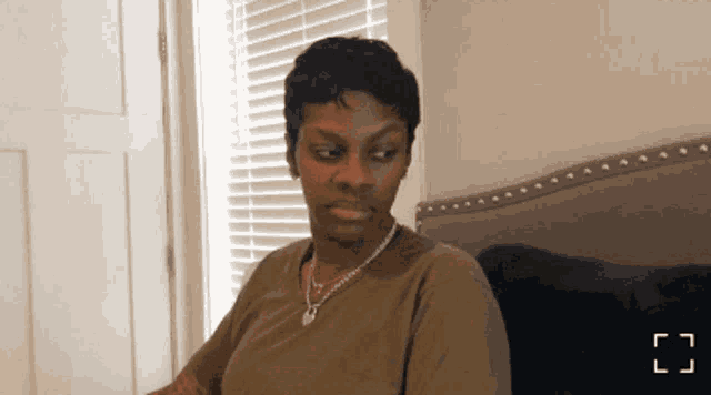 a woman is sitting on a bed with a window behind her