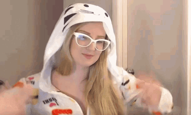 a blonde woman wearing glasses and a white hoodie with a cat on it