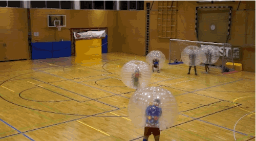 a group of people playing bubble soccer in a gym