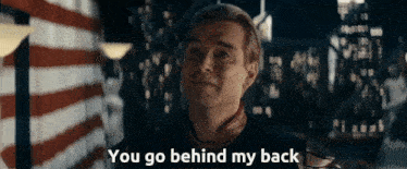 a man says " you go behind my back " while standing in front of a flag