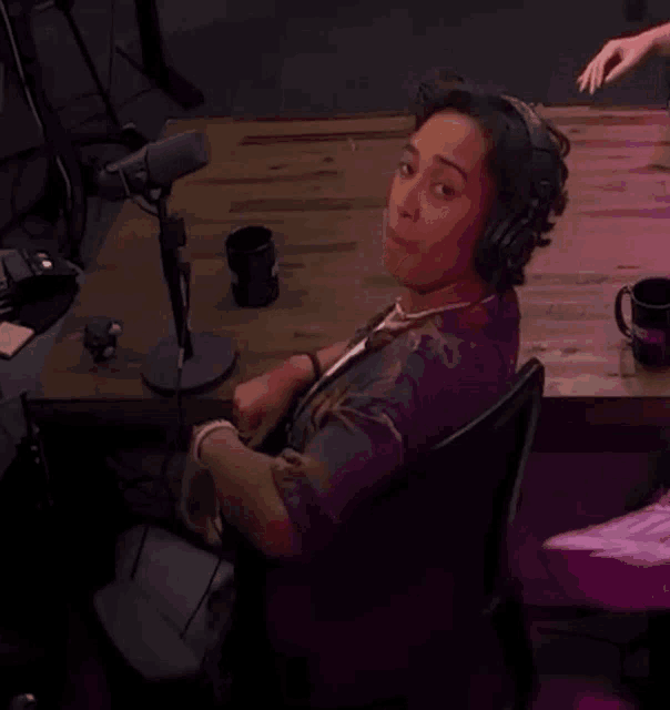 a man wearing headphones is sitting in front of a microphone .