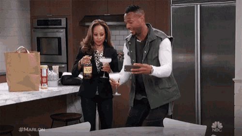 a man is taking a picture of a woman holding a martini while she holds a jar of honey .