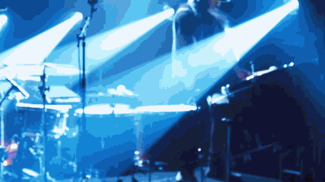 a man playing drums on a stage with a blue background