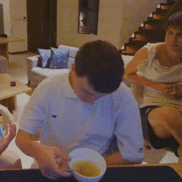 a man is sitting at a table with a bowl of soup and a spoon .