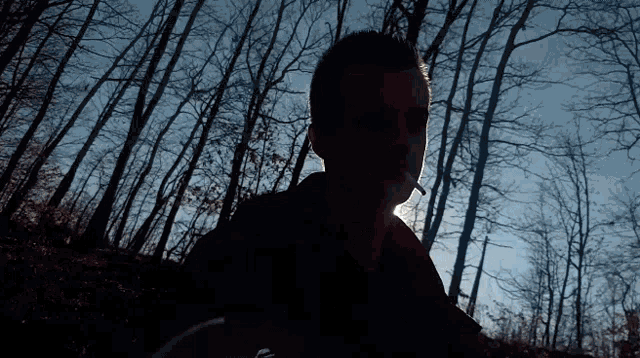 a man is smoking a cigarette in a dark forest