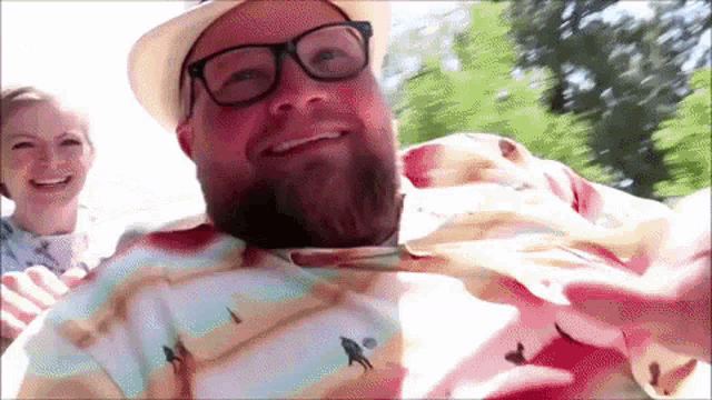 a man with a beard wearing a hat and glasses is smiling