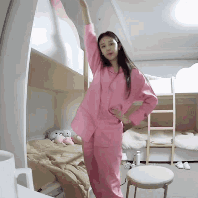 a woman in pink pajamas is standing in a bedroom
