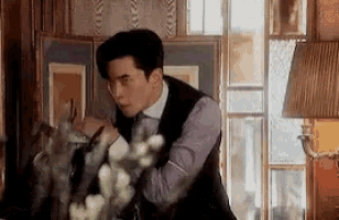 a man in a suit and tie is standing in front of a window .
