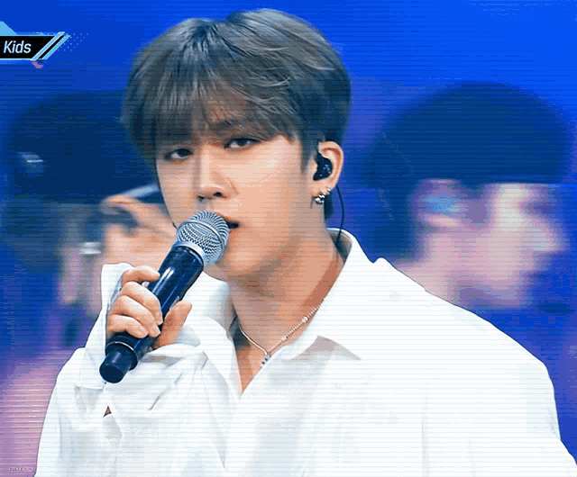 a young man singing into a microphone with the words kids on the bottom right
