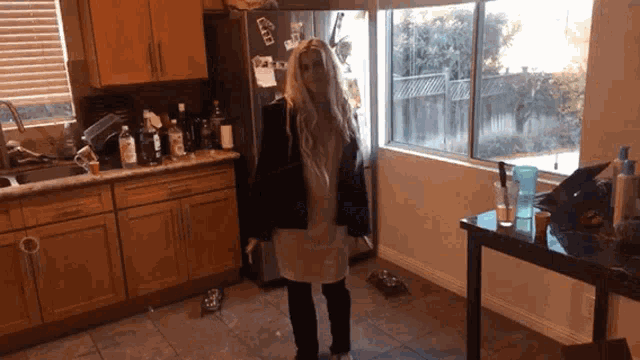 a woman standing in a kitchen with a refrigerator that says ' a ' on the door