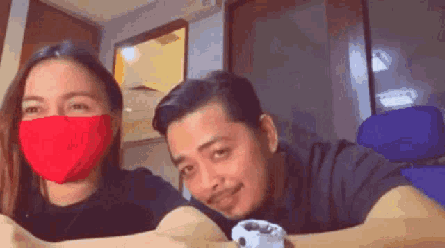 a man and a woman wearing red face masks are laying on a table .