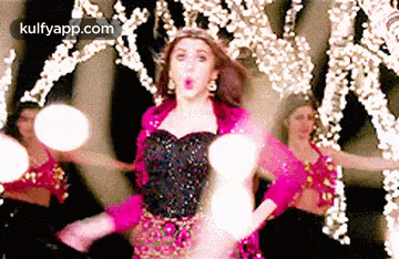a woman in a pink and black dress is dancing in front of a group of dancers .
