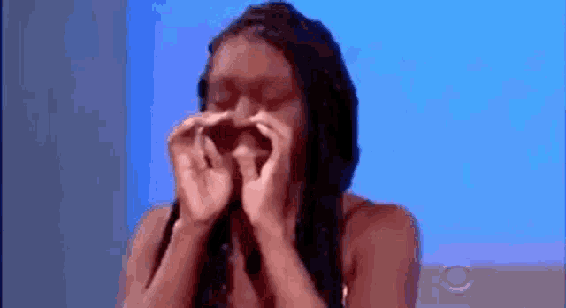 a woman is covering her face with her hands .