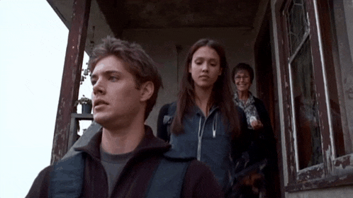 a man and two women are standing in front of a building