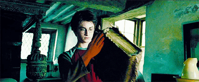 harry potter is holding a book in his hands