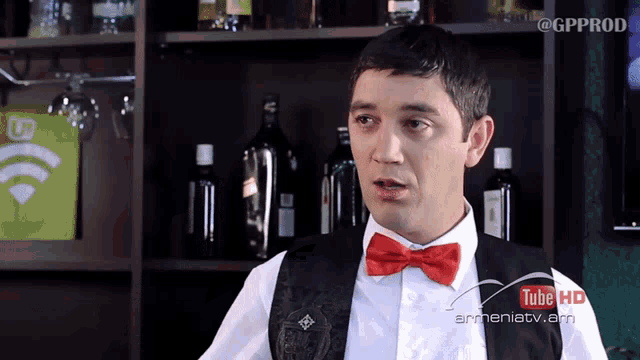 a man in a red bow tie is standing in front of a shelf with bottles of alcohol and a youtube hd logo