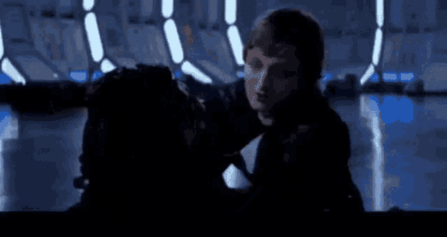 a man is holding another man 's head in a dark room in a star wars movie .