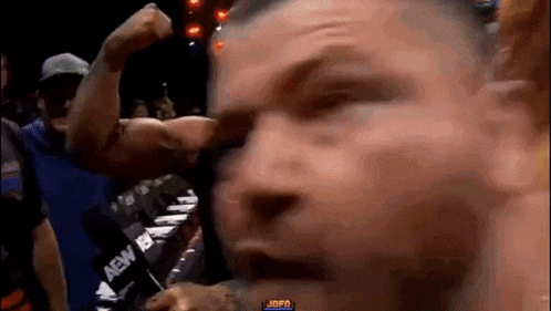 a man is flexing his muscles in front of a crowd of people at a boxing match .