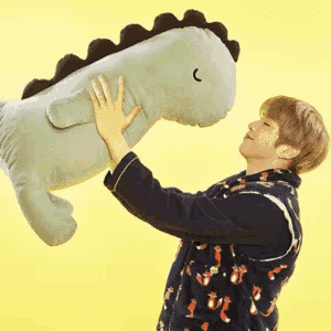 a man is holding a stuffed dinosaur with the letter c on its face